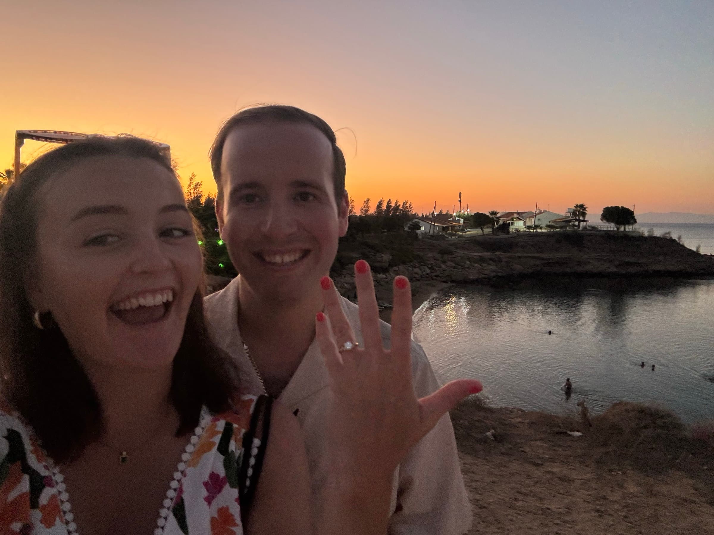 Tony and Carrie, arms around each other at sunset, celebrating their engagement